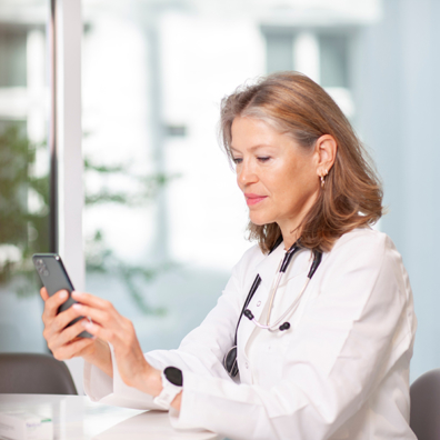 Ärtzin mit Mobiltelefon schaut auf Diagnosia App