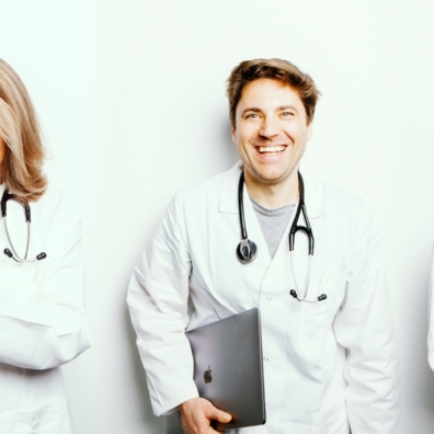 Titelbild Diagnosia App für Ärzte und Ärztinnen - zwei Ärztinnen mit Mobiltelefon und ein Arzt mit Laptop